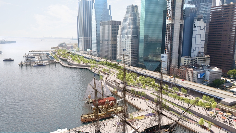 Aerial view of a waterfront cityscape with tall modern skyscrapers, a tree-lined promenade, docked historic sailing ships, and people walking along the water’s edge. Aerial view of a waterfront cityscape with tall modern skyscrapers, a tree-lined promenade, docked historic sailing ships, and people walking along the water’s edge.