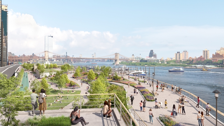 People walk, relax, and enjoy the greenery along a waterfront park with trees and paths. Boats travel on the river, and city buildings and bridges are visible in the background under a blue sky.