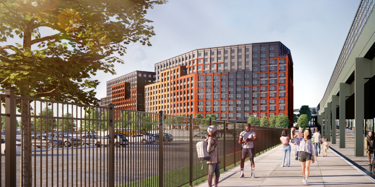 Conceptual Rendering of Willets Point housing. A modern urban scene with people walking on a sidewalk next to a fence. Two large, multistory buildings with red and brown facades are visible. A tree provides greenery, and a blue sky is above. A parking area is partially visible.