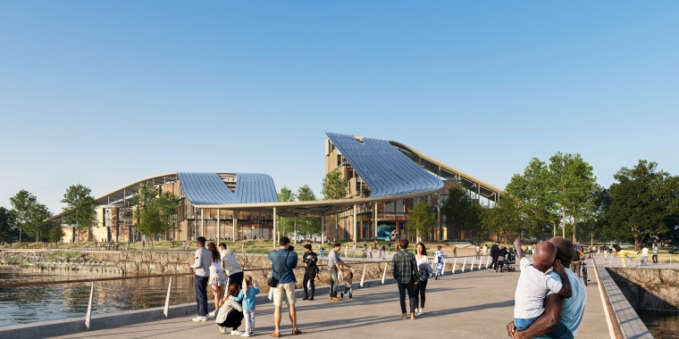 Exterior render of New York Climate Exchange on Governors Island shows people walking and gathering on a wide path near water, with modern, glass-roofed buildings and green trees in the background under a clear blue sky.